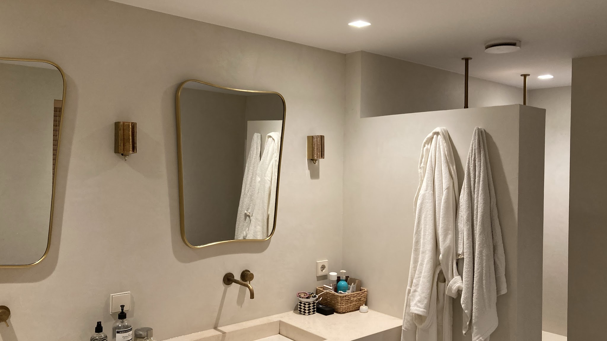 Badkamer met wanden in lichte betonlook, ronde spiegels en een wastafel