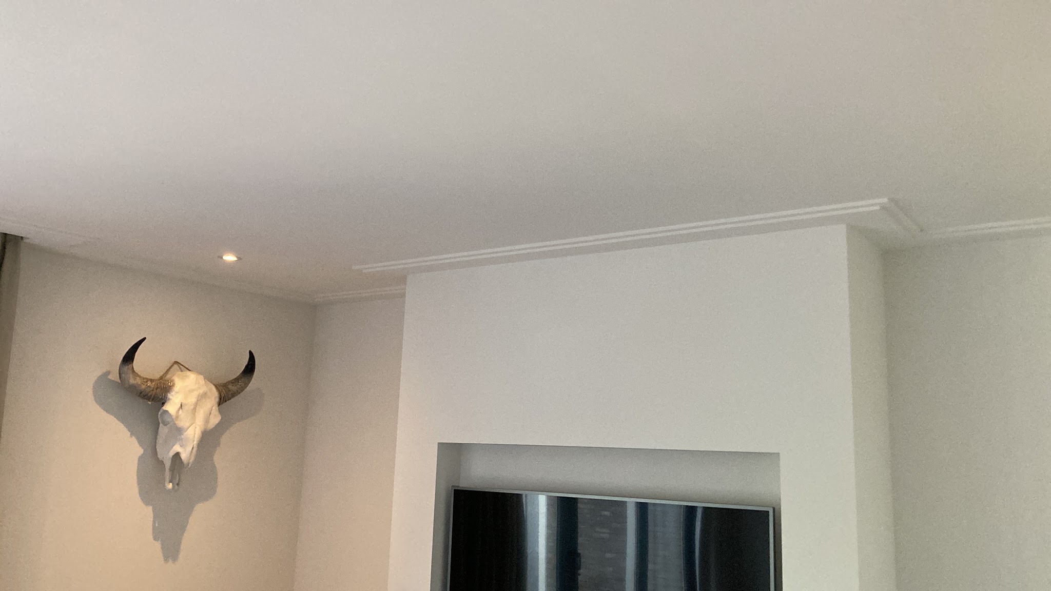 Strak gestuukte wanden en plafond met een lijst rond een tv-nis