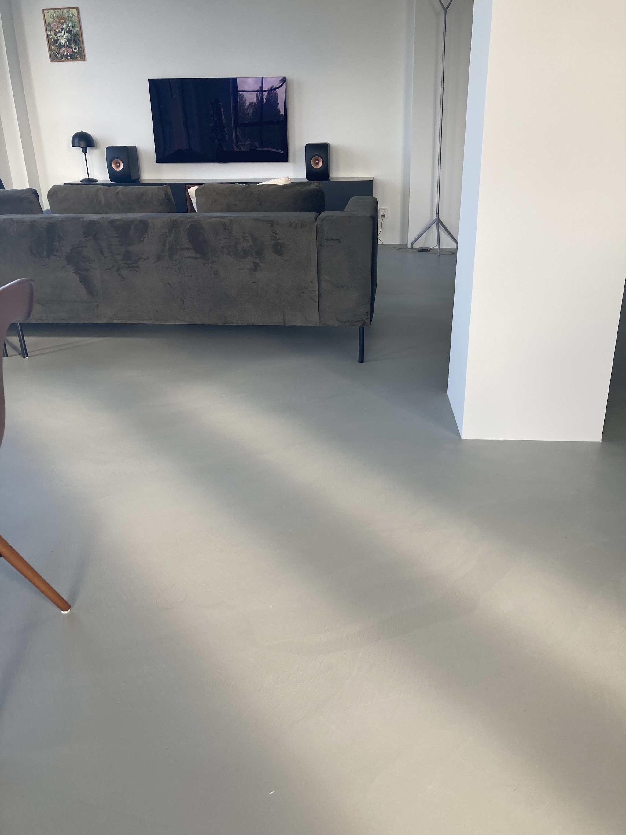 Woonkamer met grijze gladde vloer, een bank en een tv