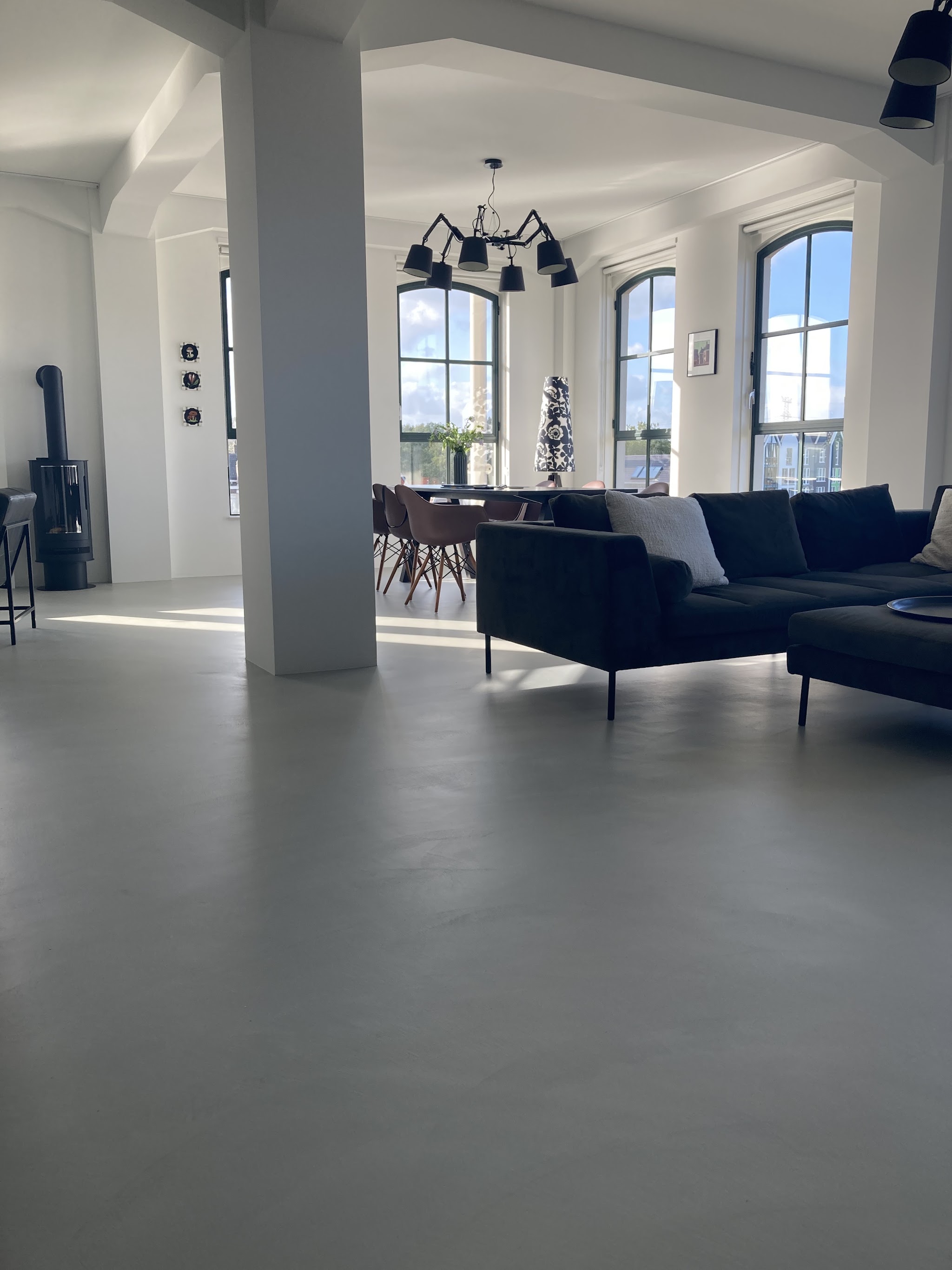 Ruime loft met boograamen, een zithoek en een grijze naadloze vloer